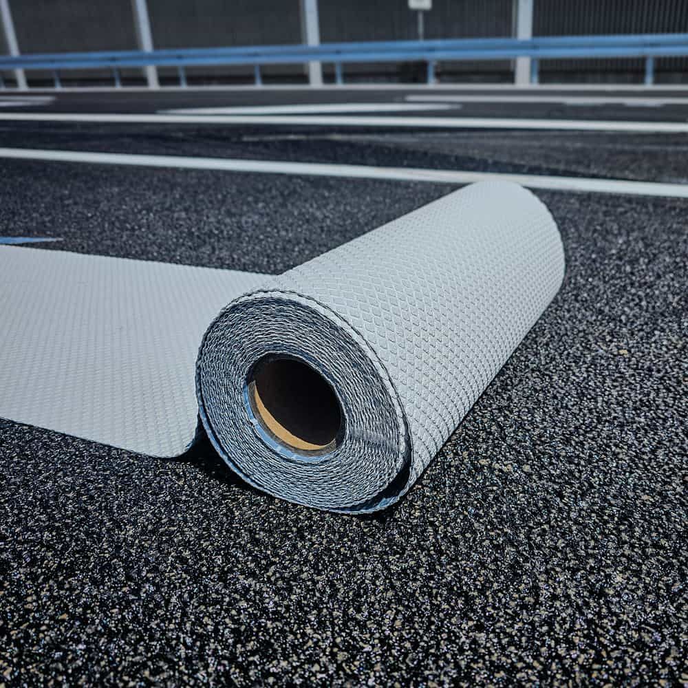 Rolle weißer Fahrbahnmarkierungsfolie auf Asphaltoberfläche vor dem Aufbringen