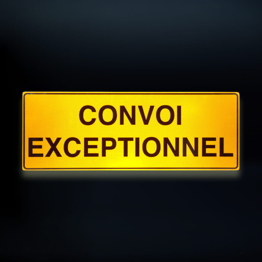 Reflektierendes Schild „Convoi Exceptionnel“ bei Dunkelheit, leuchtend gelb