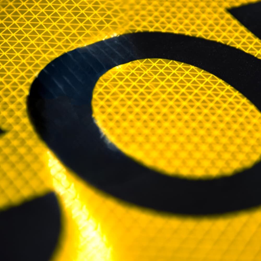 Makroaufnahme reflektierender Folie mit schwarzem Schriftzug "CONVOI EXCEPTIONNEL"