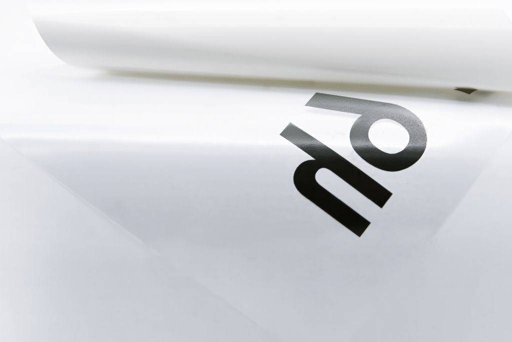 Nahaufnahme eines transparenten Overlays mit schwarzem Druck und abgelöster Folienkante