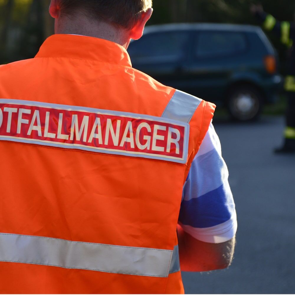 Orange Warnweste mit silbernem 3M Scotchlite 8925 Reflexband und Aufschrift „NOTFALLMANAGER“