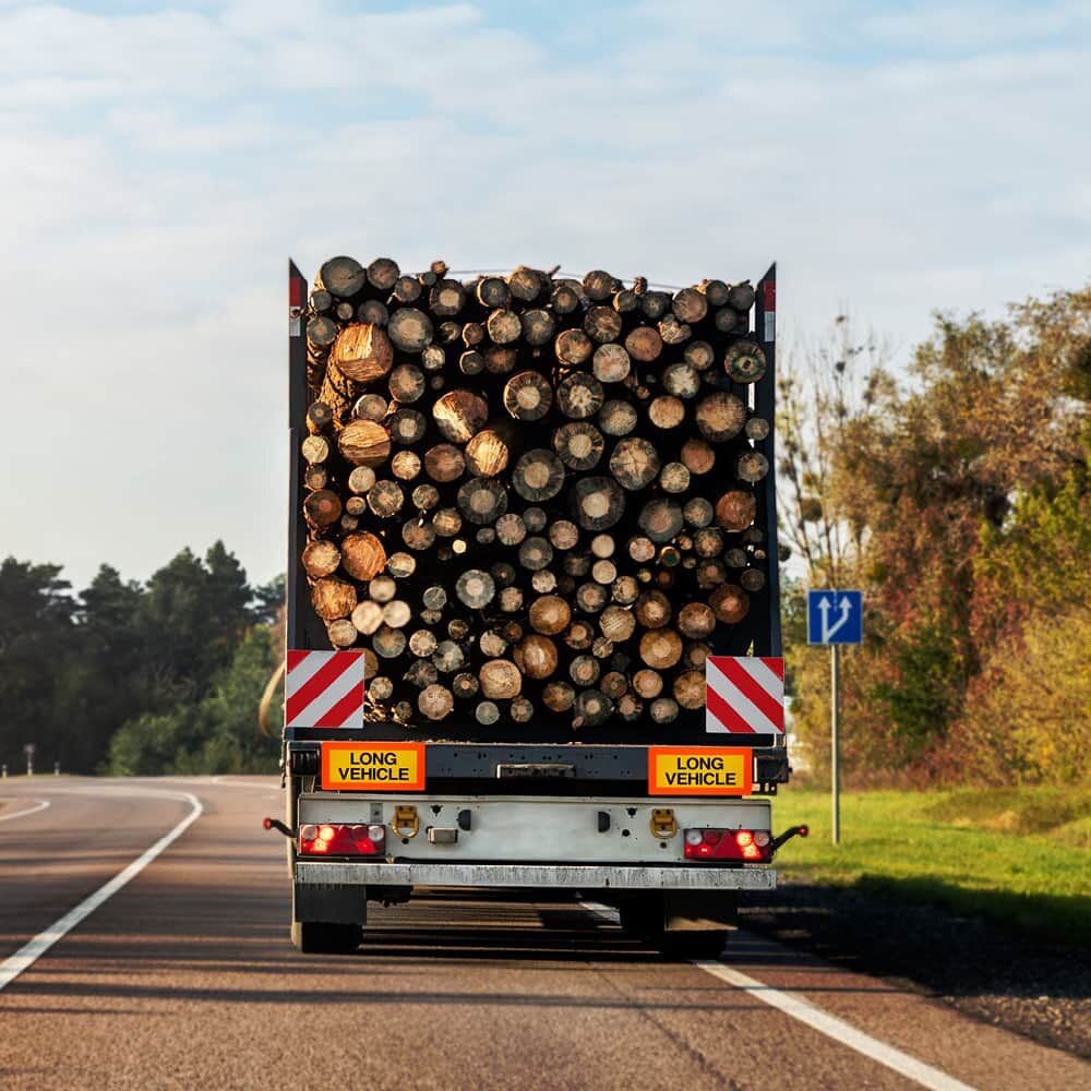 Zwei Long Vehicle Tafeln montiert an Holztransport auf Landstraße