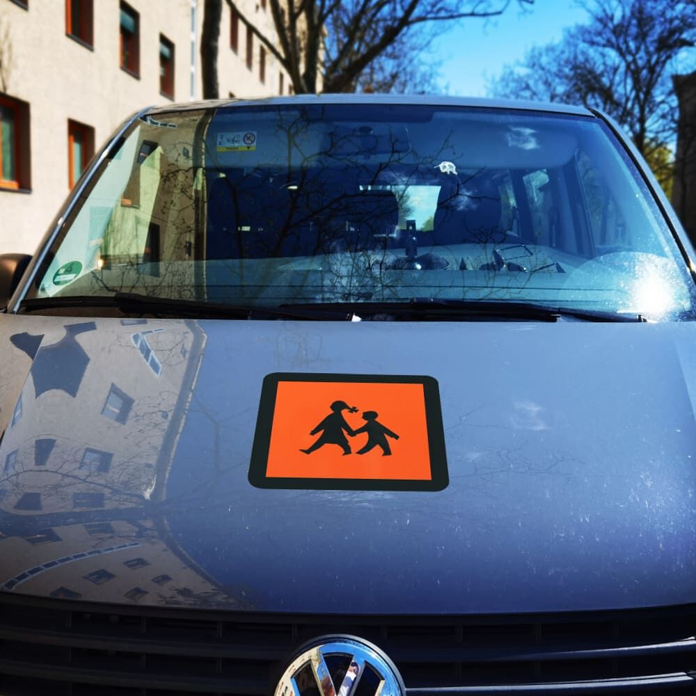 Reflektierendes Schulbusschild mittig auf der Motorhaube eines Fahrzeugs angebracht