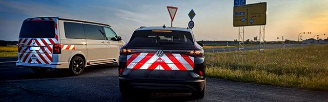 Konturgeschnittene Warnmarkierungssätze für Fahrzeuge mit Sonderrechten Zwei Fahrzeuge mit reflektierenden Kfz-Warnmarkierungssets sind bei Dämmerung auf der Straße unterwegs.