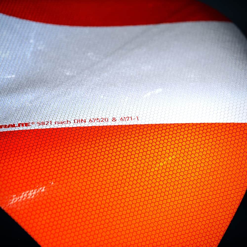 Reflektierende Folie im Licht mit rot-silbernem Muster und Mikroprismenstruktur