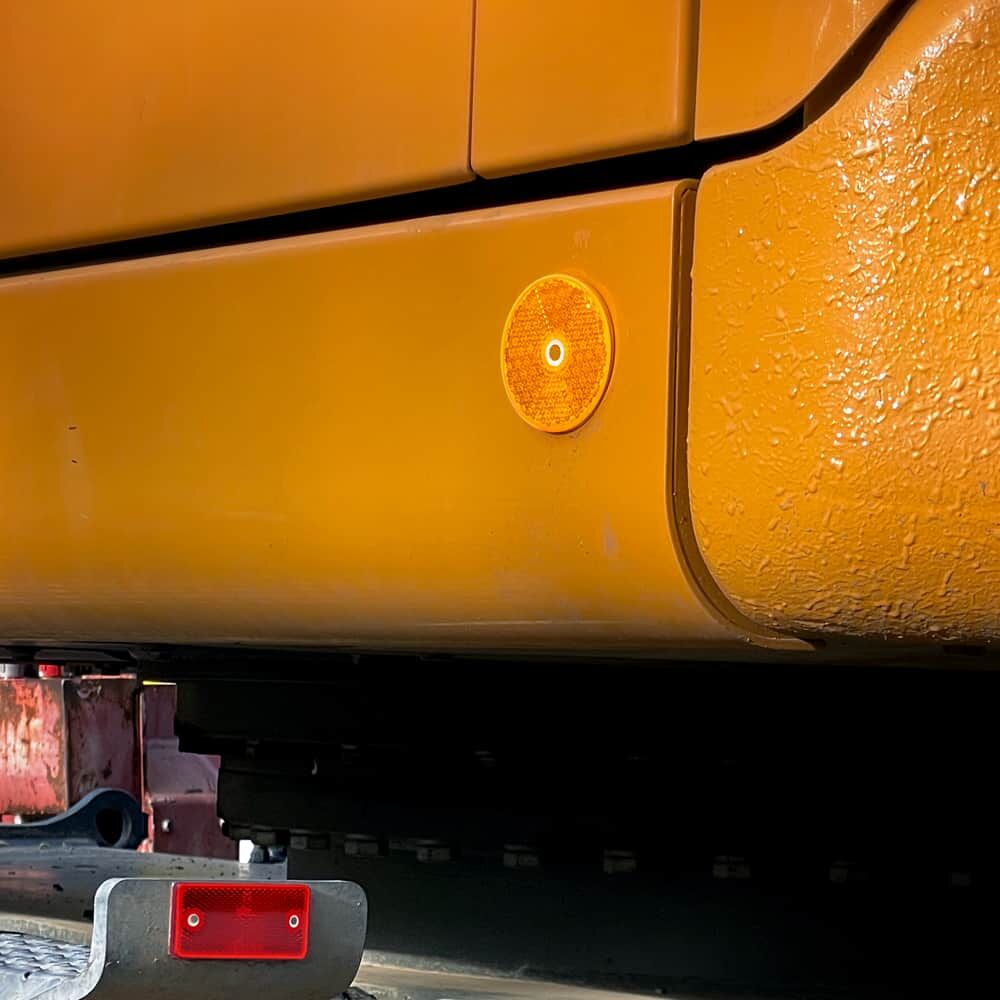 Orange Reflektor Ø60 mm mit Bohrloch an gelber Baumaschine montiert