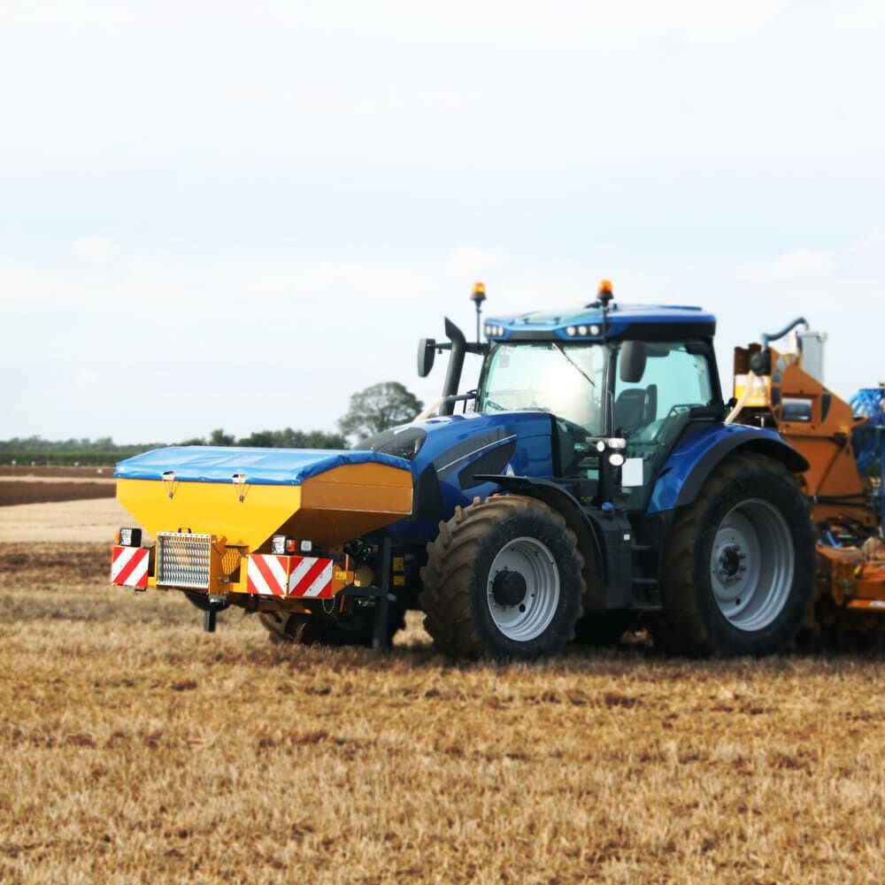Traktor mit Heckstreuer, beklebt mit Rot-Weiß Orafol ORALITE 5421 Warnmarkierung