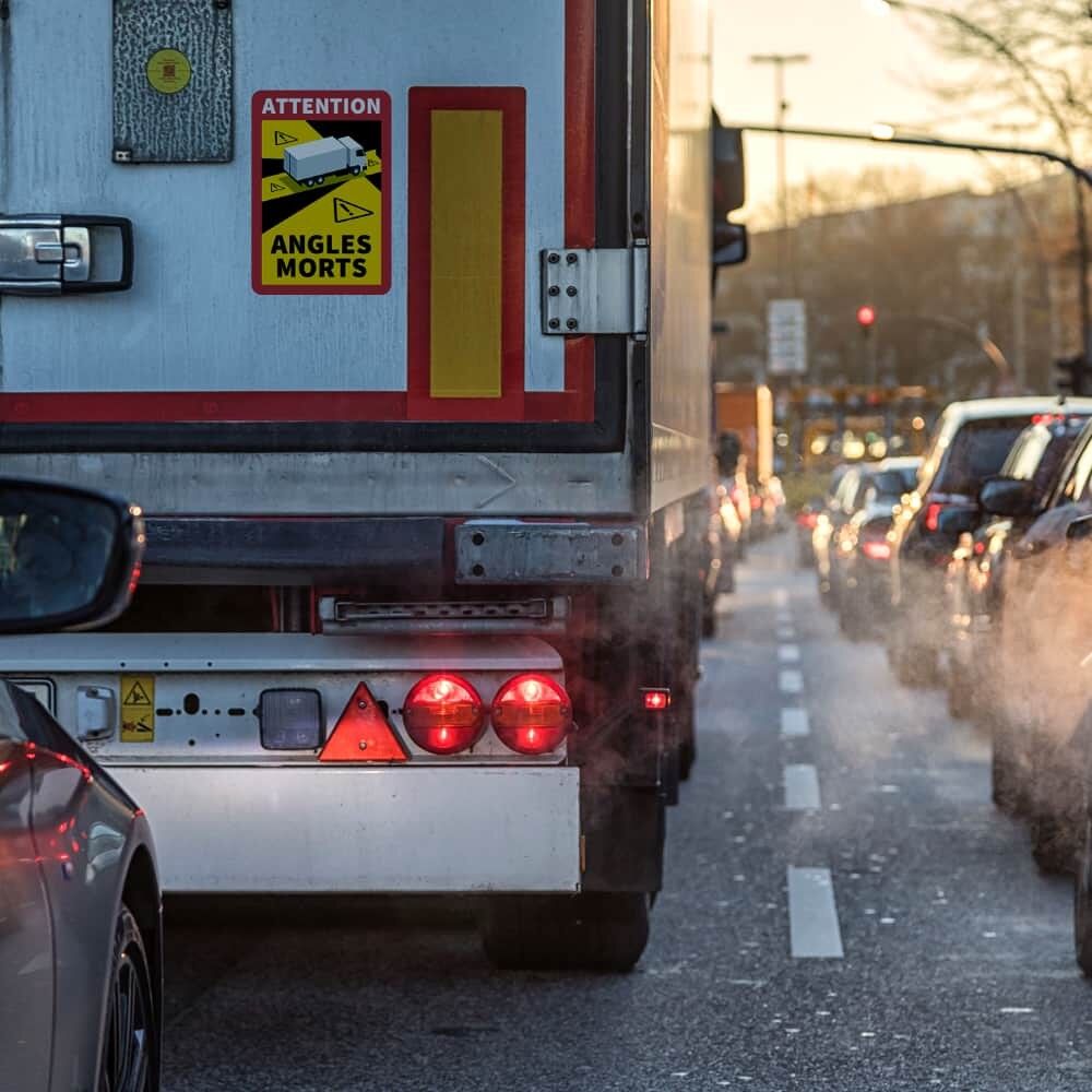 „Angles Morts“-Schild auf LKW-Heck im Stadtverkehr bei Dämmerung