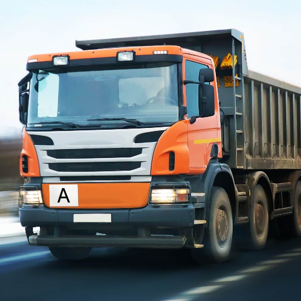 Permanenter A-Aufkleber an Front eines orangefarbenen Kipper-Lkw im Einsatz