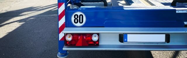 Geschwindigkeitsschilder gemäß § 58 StVZO Rückseite eines blauen Anhängers mit 80 km/h Schild, Warnmarkierung und Rückleuchten