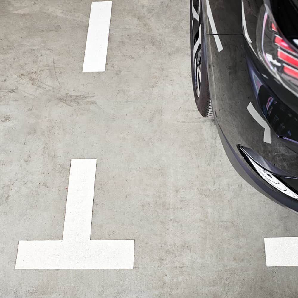 T-Markierung aus 3M Stamark Folie auf Betonboden zwischen Parkplätzen