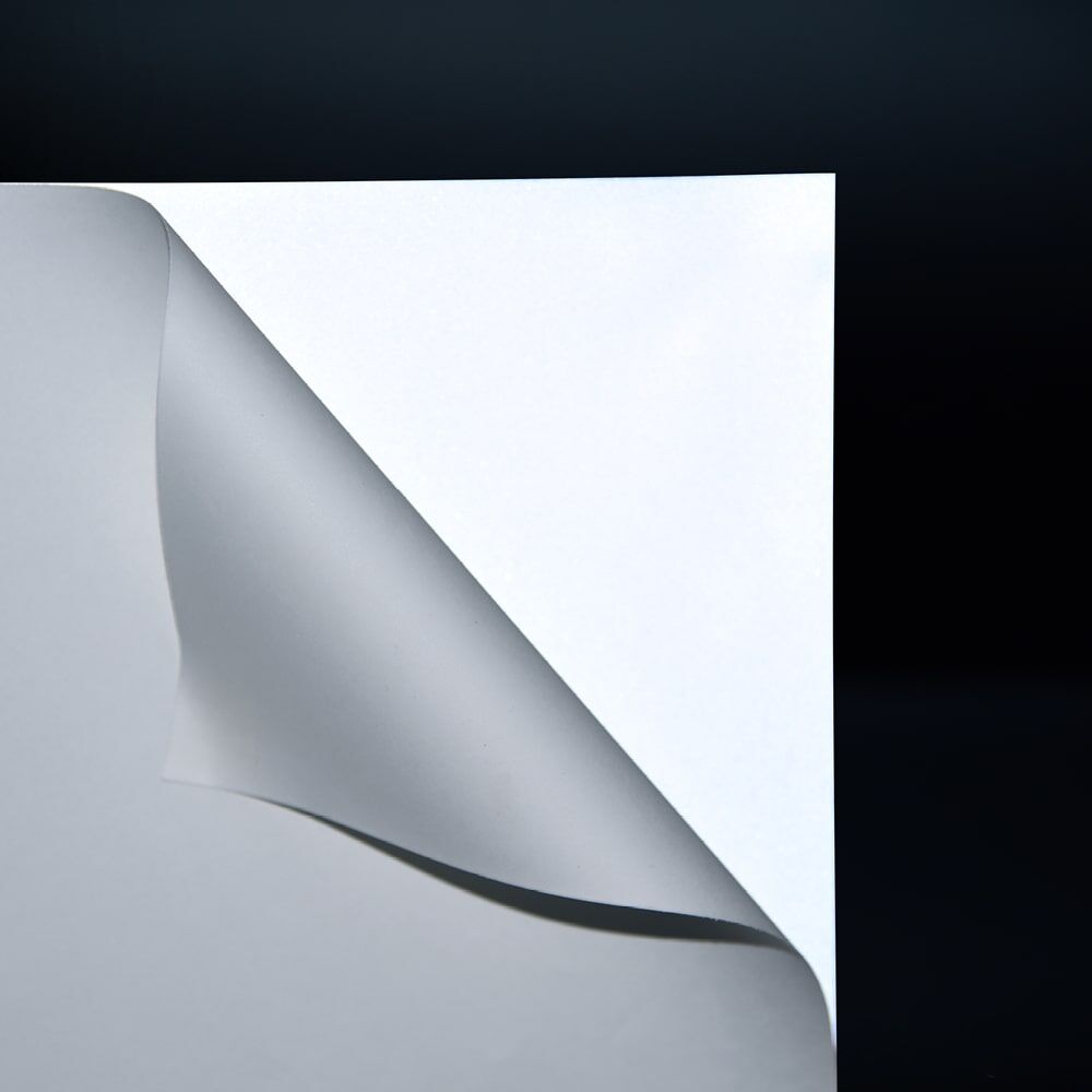 3M Scotchlite 8725, Ecke abgelöst, zeigt starke Reflexwirkung unter Licht bei Dunkelheit
