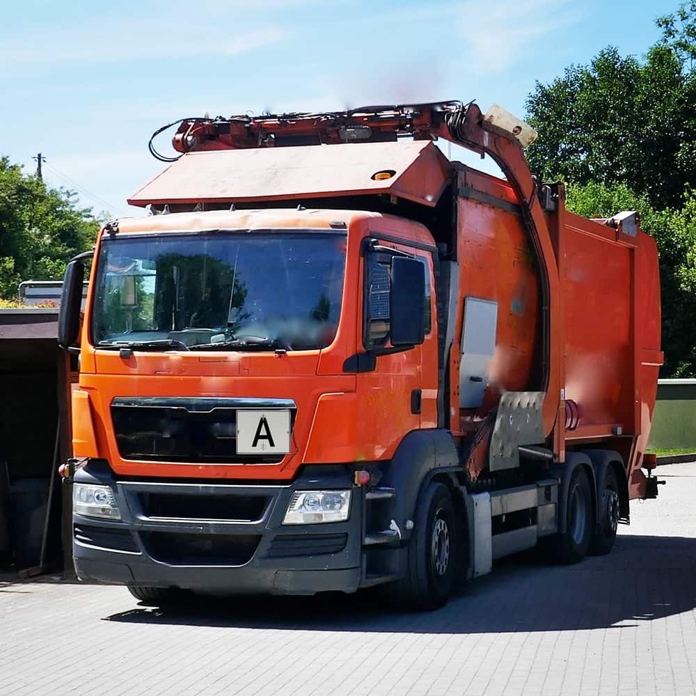 Oranger Entsorgungs-Lkw mit vorne montiertem Aluminium-A-Schild im Arbeitseinsatz.