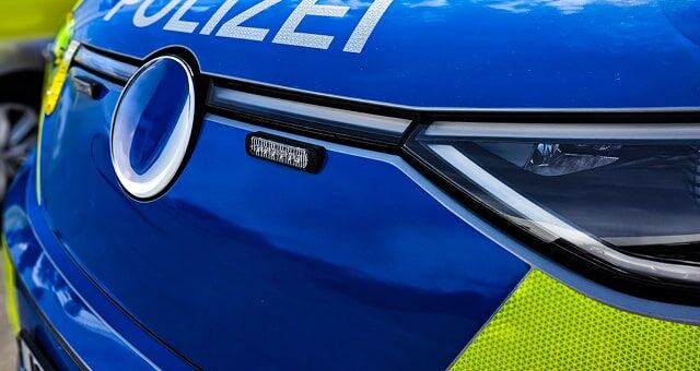 Nahaufnahme eines blauen Polizeiwagens mit reflektierendem Schriftzug und Scheinwerfer