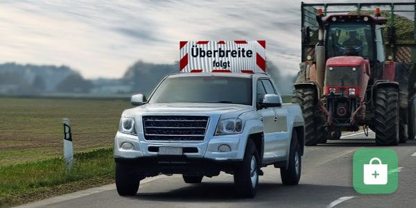 Pickup als Begleitfahrzeug von Landmaschine mit Überbreite folgt Schild