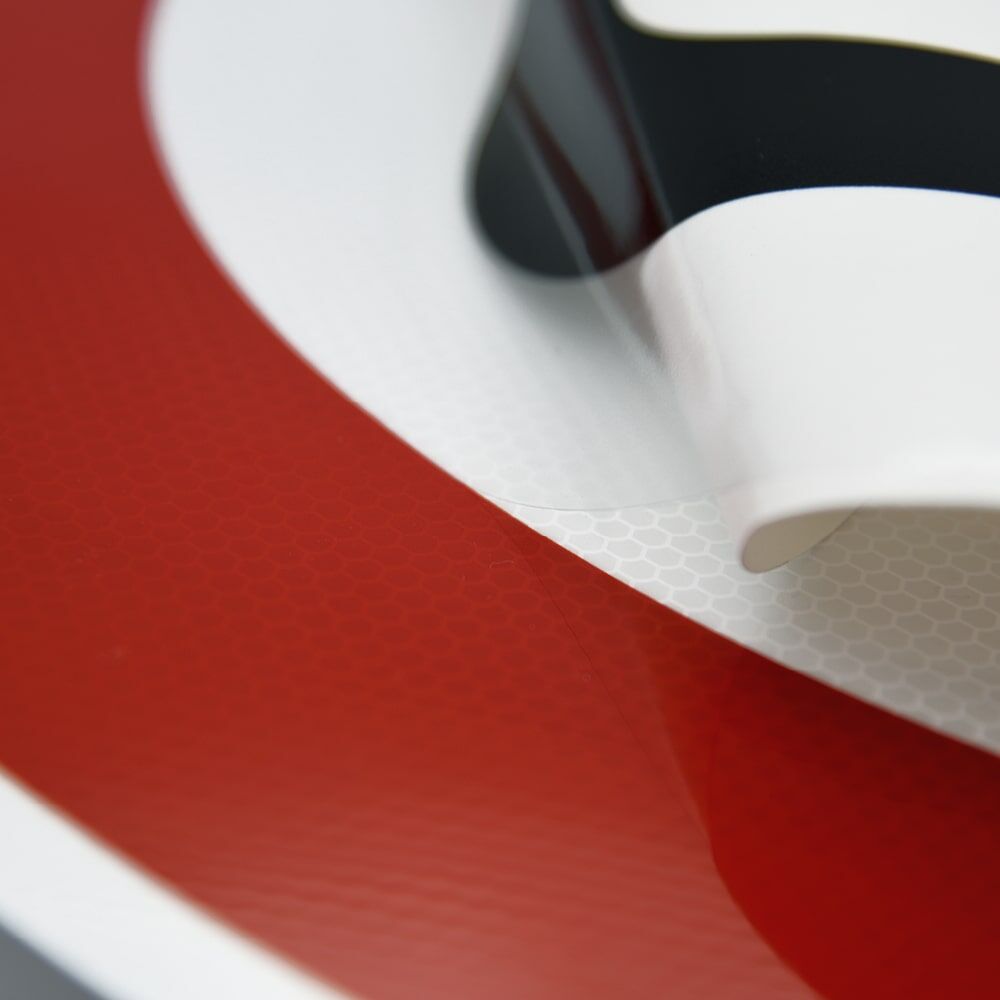 Overlay-Folie ablösbar: Ecke angehoben, Zusatzschild darunter sichtbar