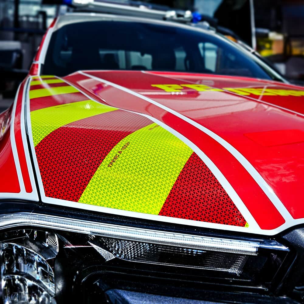 Gelb-rote ORALITE VC612 Konturmarkierung auf roter Motorhaube eines Einsatzwagens