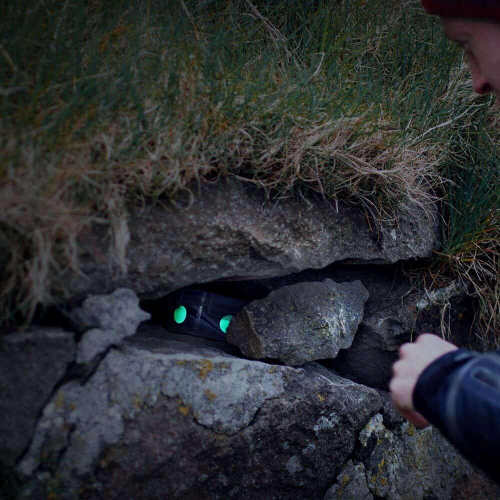 Leuchtende Geocaching Reflektoren kennzeichnen Versteck zwischen Steinen