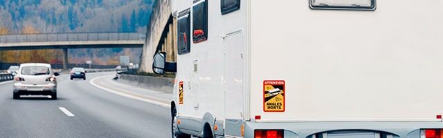 Bild zeigt ein Wohnmobil auf der Autobahn im Anschnitt aus Heckperspektive mit Angles Morts-Schild