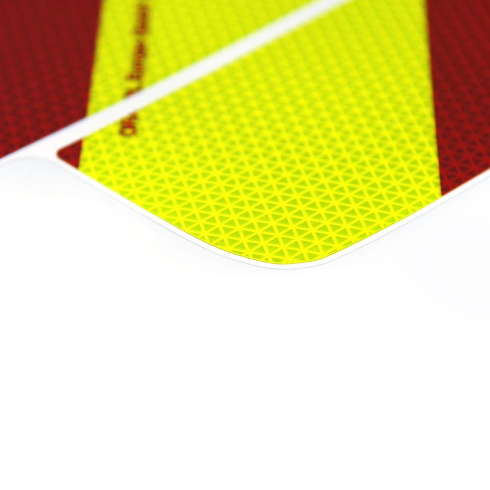 Makroaufnahme einer fluorlime-roten Warnmarkierung mit feinem Mikroprismen-Raster mit Fokus auf Ecke