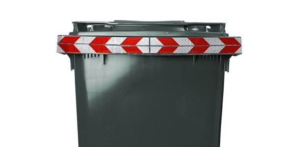 Ein grauer Müllcontainer mit reflektierendem rot-weißem Warnstreifen am oberen Rand.
