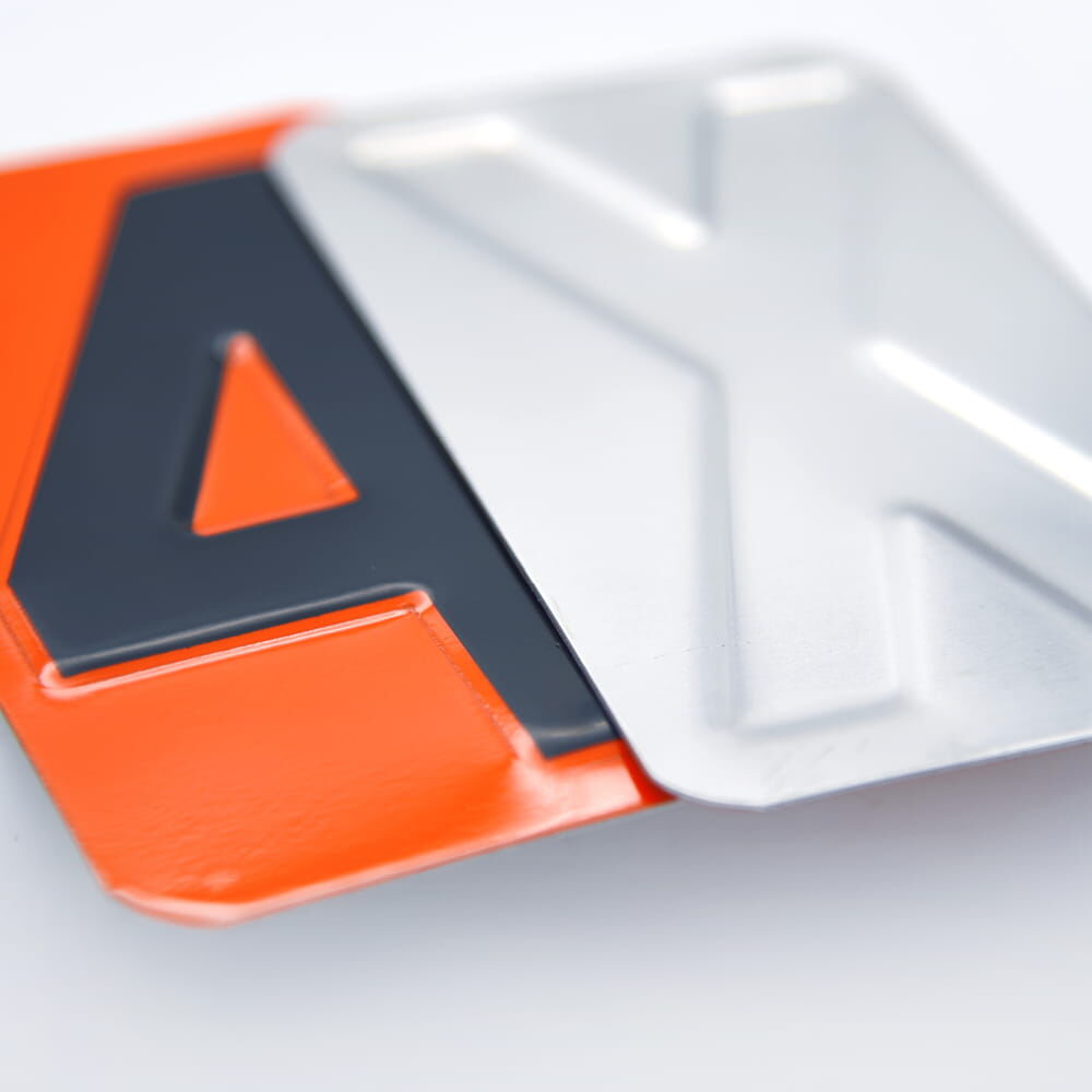 Nahaufnahme zweier ADR-Ziffernplättchen, Vorderseite orange mit Schwarz, Rückseite silber.
