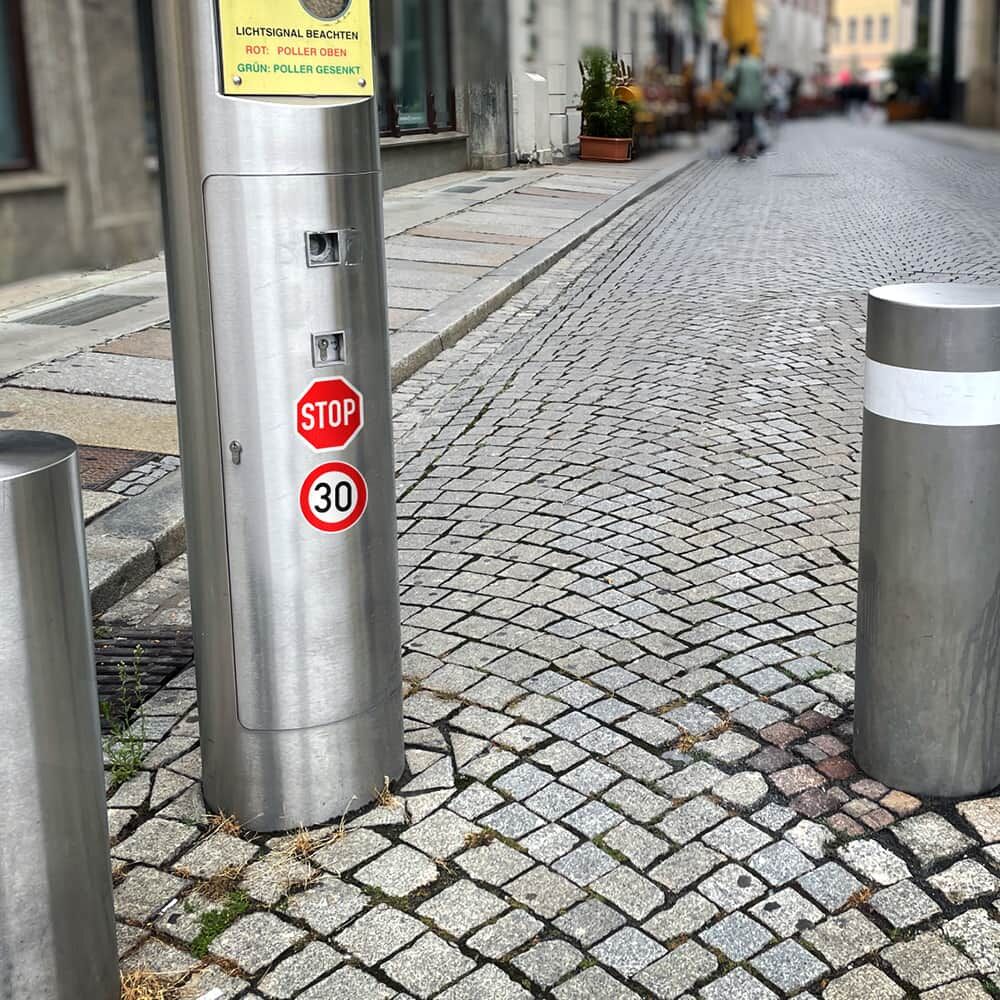Stop- und Tempo-30-Aufkleber auf Edelstahlpoller einer Fußgängerzone