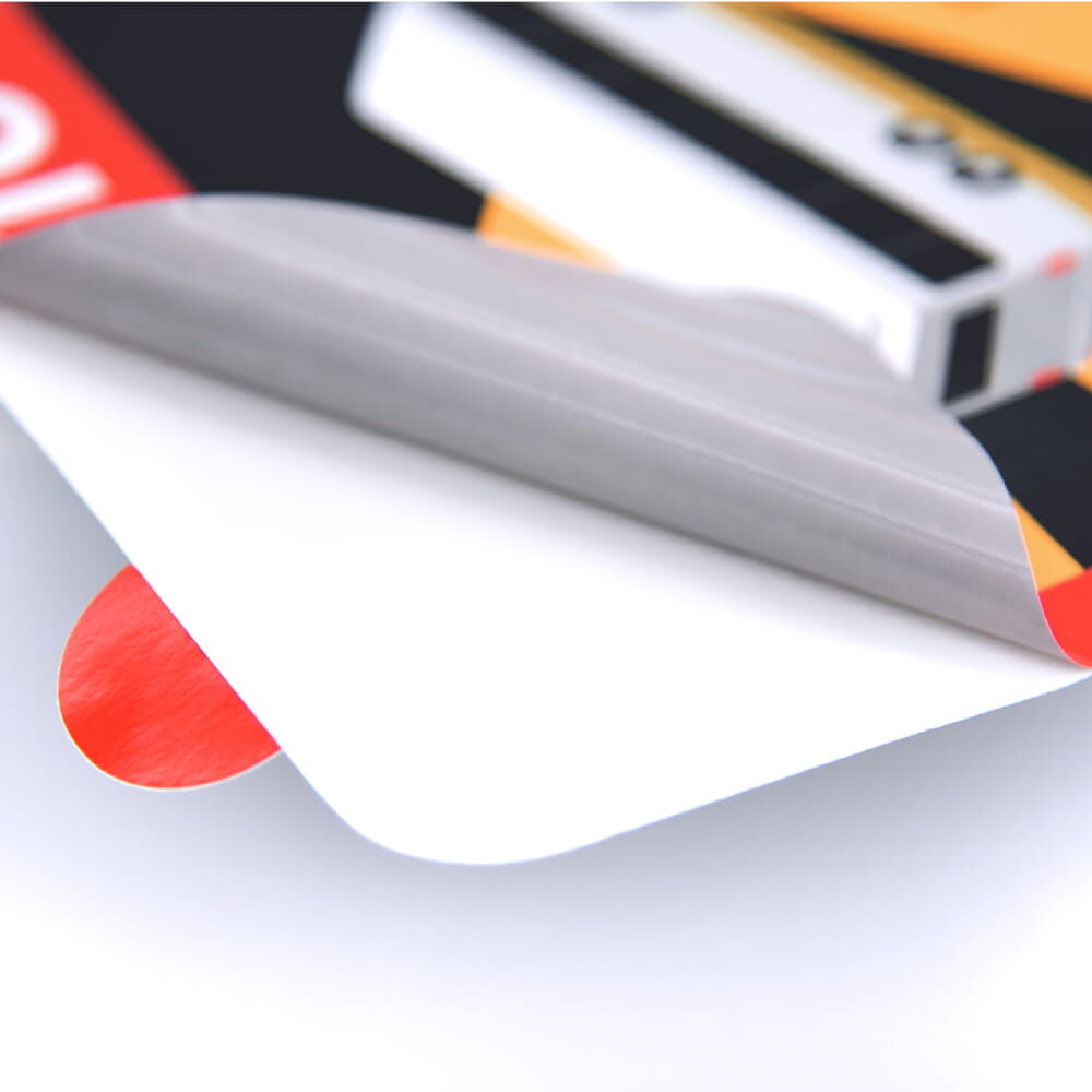 Rückseite des Aufklebers teilweise abgezogen, rote Vorderseite leicht sichtbar auf weißem Träger