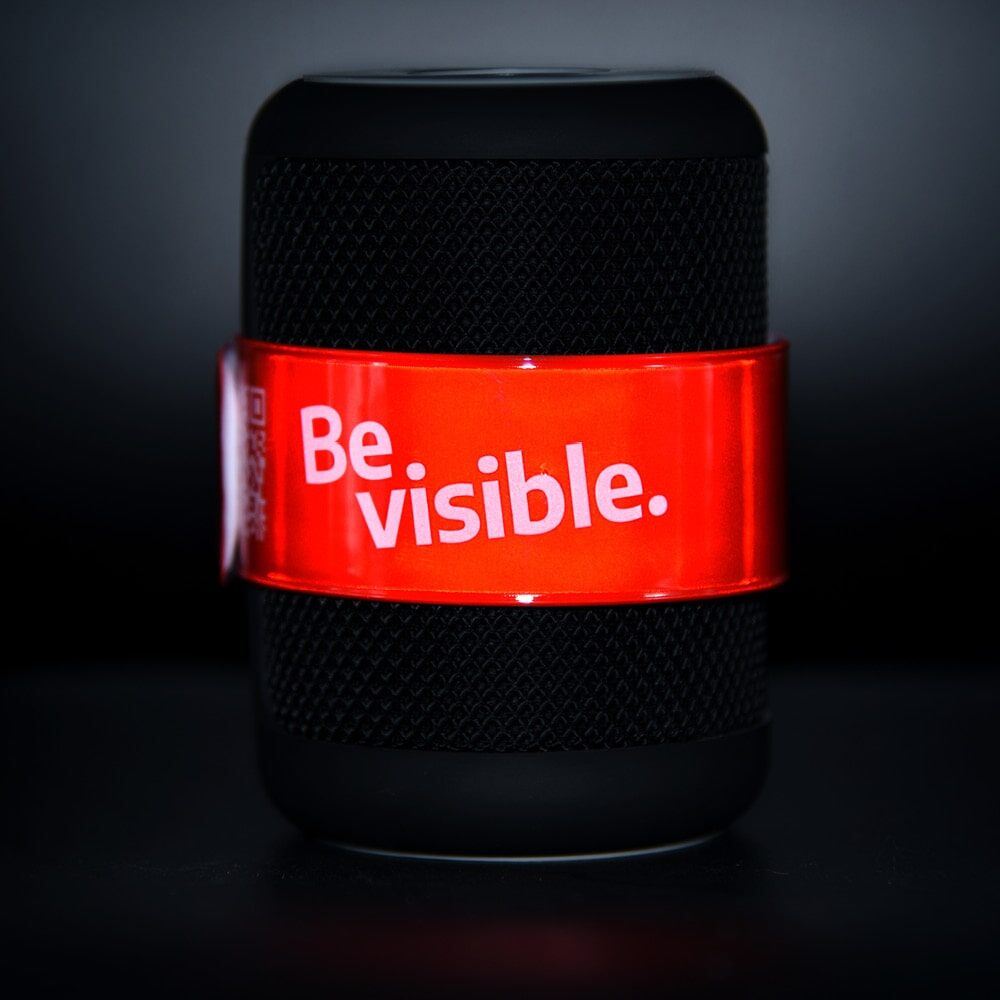 Rotes Schnapparmband mit Logo um schwarzen Lautsprecher gelegt