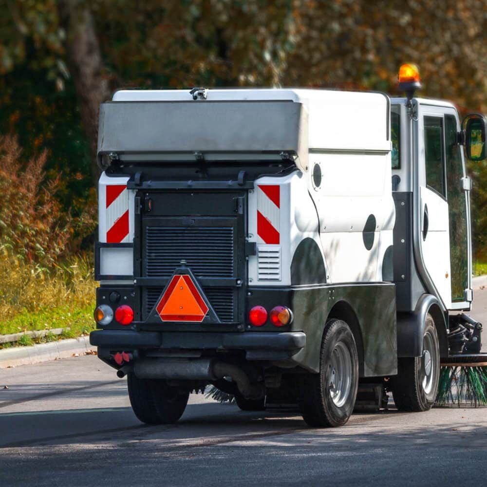 Warntafel an Straßenreinigungsfahrzeug bei Tageslicht auf befestigter Straße