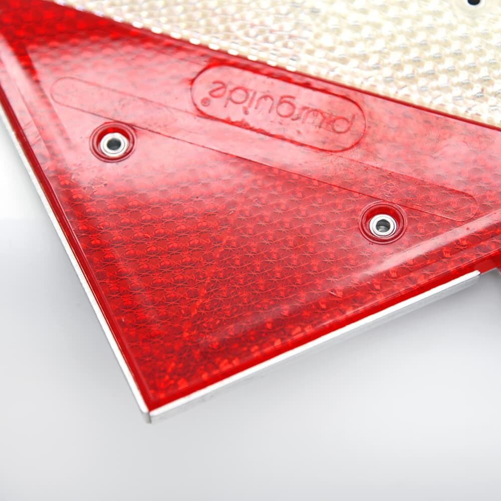 Detail: Prismenreflexfolie rot, zwei Ösen und Kantenprofil in Nahaufnahme