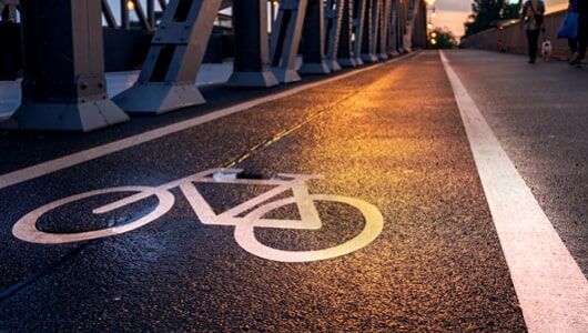 Abschnittstitelbild zu Piktogramme für den städtischen Bereich Das Bild zeigt eine mit aus Fahrbahnmarkierungsfolie gekennzeichnete Fahrradspur auf einer Brücke bei Dämmerung
