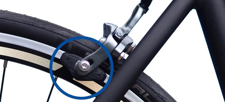 Nahaufnahme einer Fahrradbremssattelbefestigung an der Felge, wobei ein blauer Kreis einen bestimmten Befestigungspunkt hervorhebt.