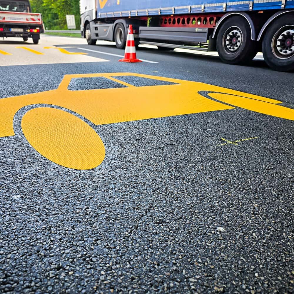 Gelbes Pkw-Piktogramm aus 3M Stamark appliziert auf dunklem Fahrbahnbelag