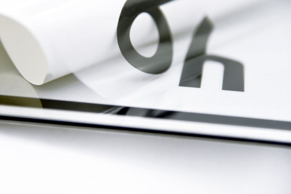 Detail eines verklebten Overlays mit schwarzem Druck und teilweise abgezogener Folie