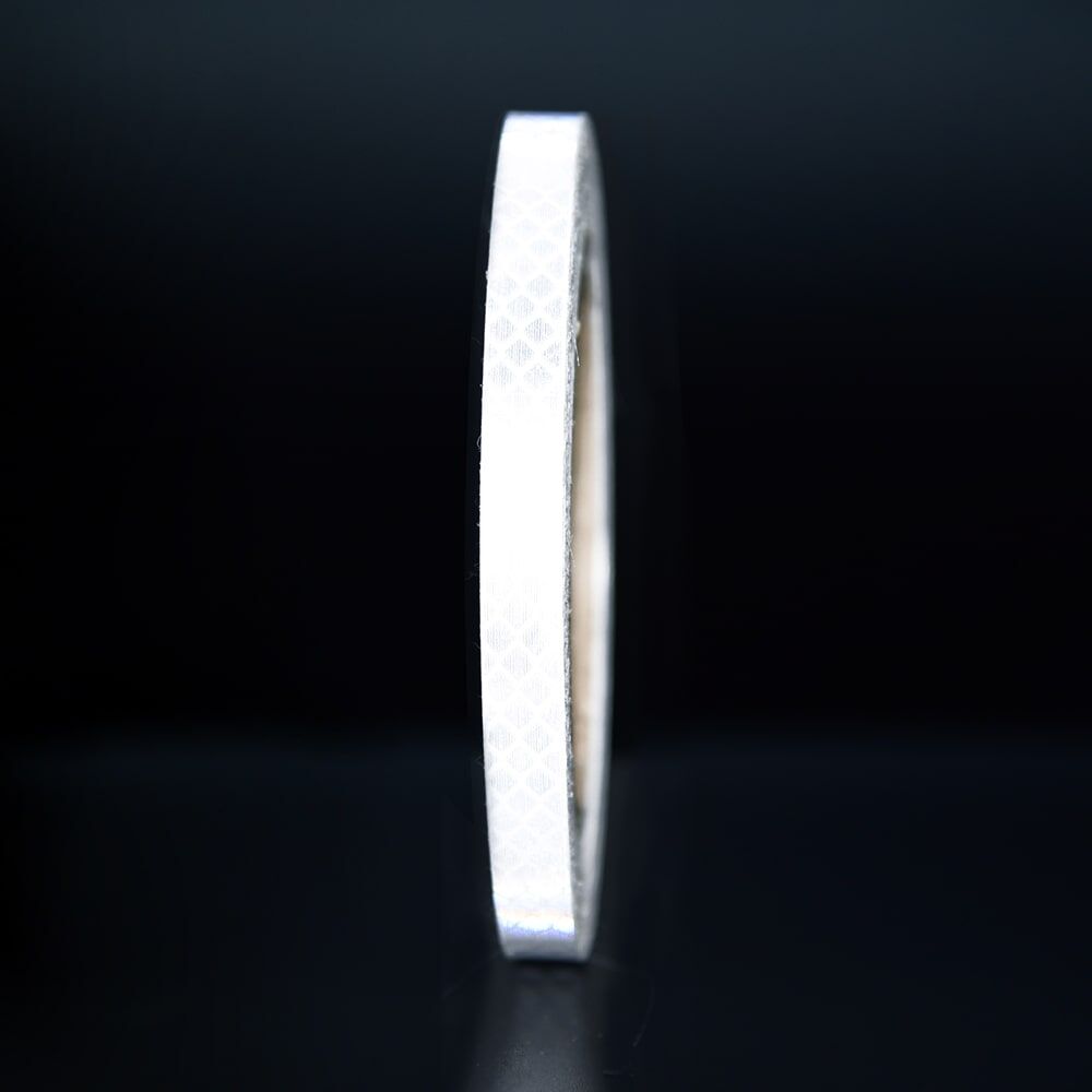 10 mm Rolle 3M Reflexband 4090 weiß, reflektierend vor dunklem Hintergrund