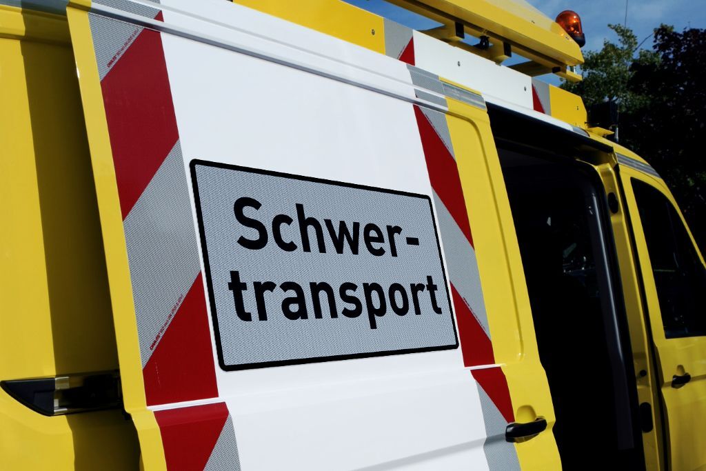 Schwertransportschild auf gelbem Begleitfahrzeug mit rot-weißer Warnmarkierung