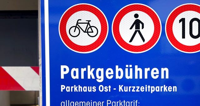 Ein blaues Hinweisschild für Parkgebühren im Parkhaus Ost mit Verbotsschildern für Fahrräder und Fußgänger.