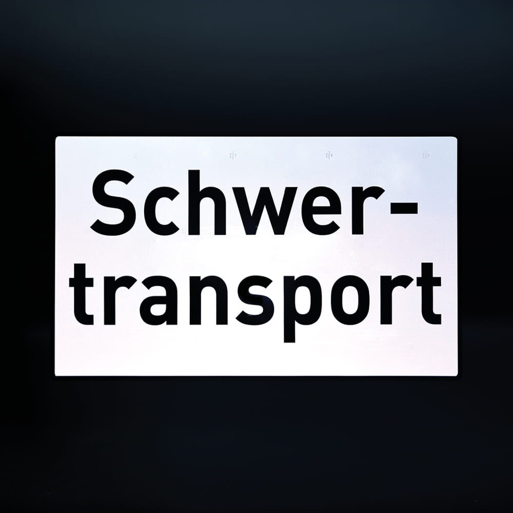 Reflektierendes Schild „Schwertransport“ vor dunklem Hintergrund
