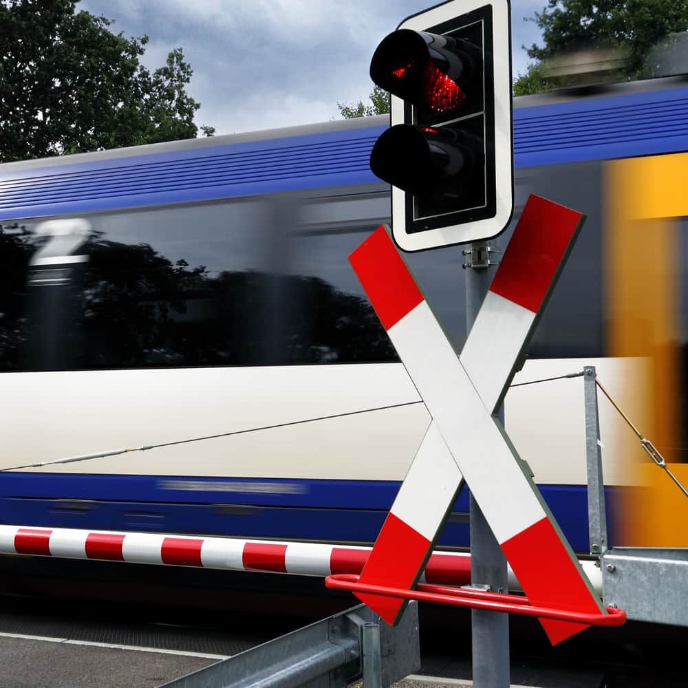 Andreaskreuz mit RA3/C Folie am Bahnübergang, vorbeifahrender Zug