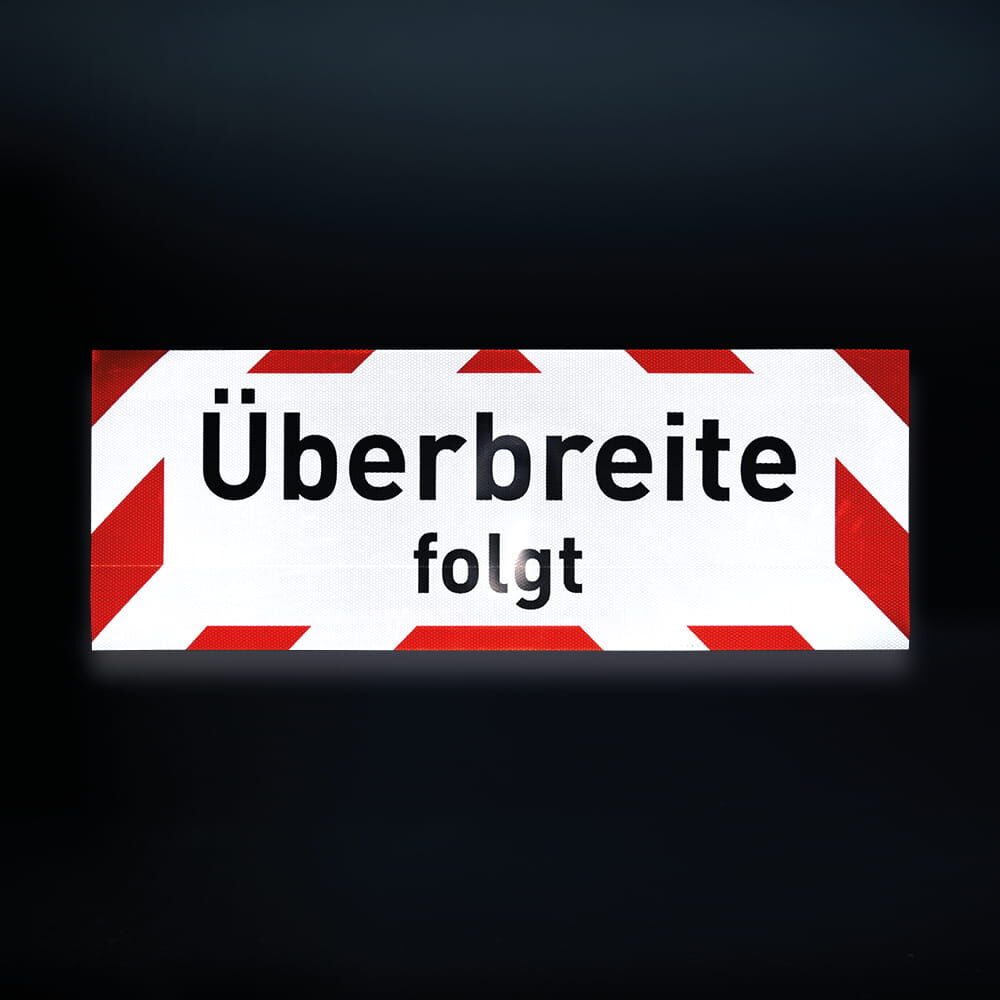Hinweisschild „Überbreite folgt“ bei Nacht, Reflexion gut sichtbar