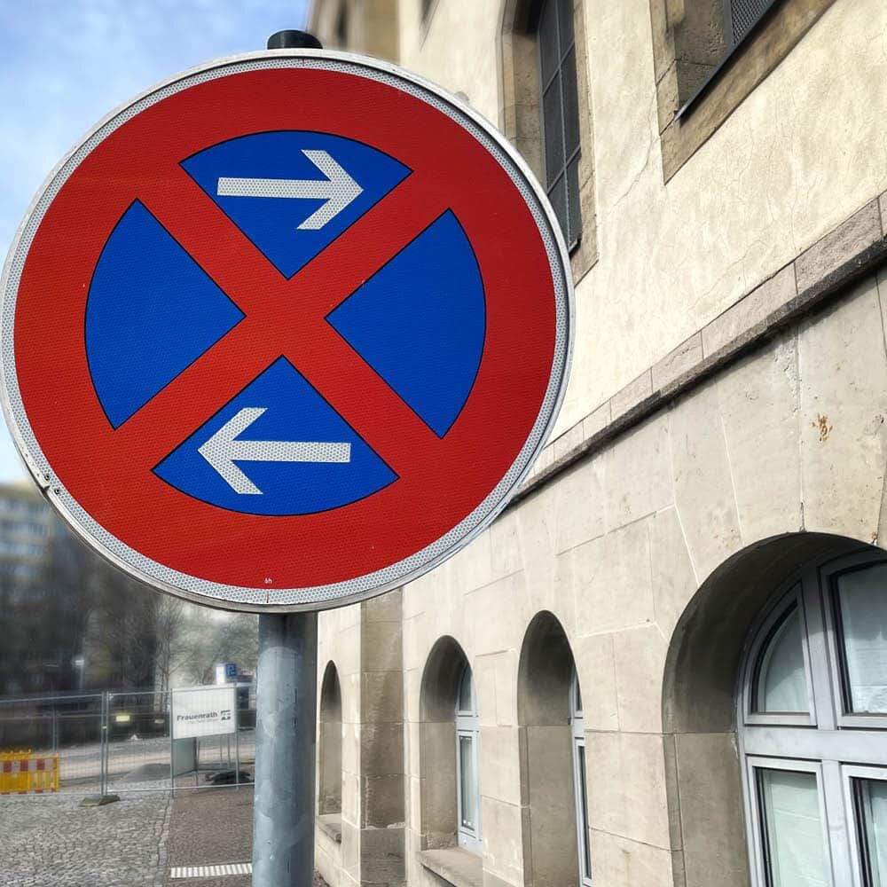 Aufgestelltes Haltverbot-Schild mit Pfeilen links/rechts an Gebäude
