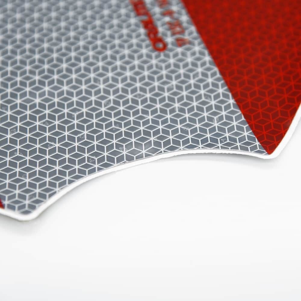 Makroaufnahme der Kante einer rot-silbernen reflektierenden Warnmarkierung