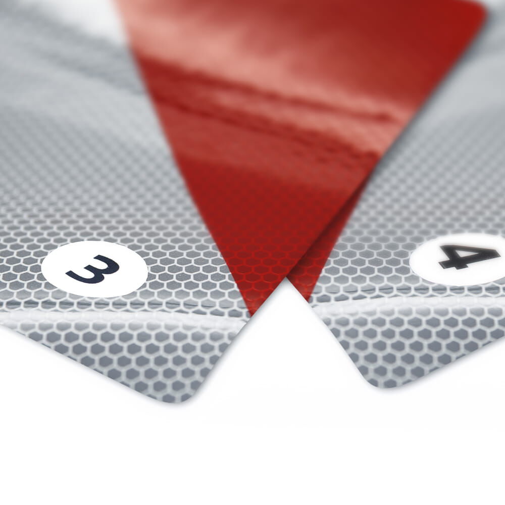 Nahaufnahme einer Warnmarkierung mit präzisem Entlastungsschlitz und Reflexstruktur