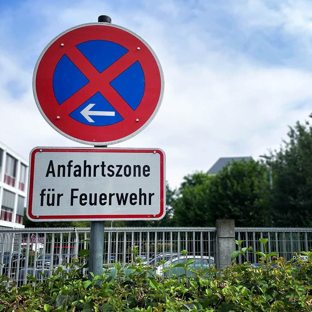 Halteverbot links mit Zusatzschild „Anfahrtszone für Feuerwehr“ am Mast