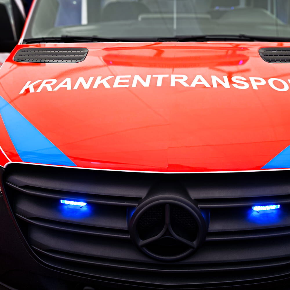 Front eines Krankentransporters mit roter ORACAL Fluorfolie 7510 Premium und blauen Akzenten