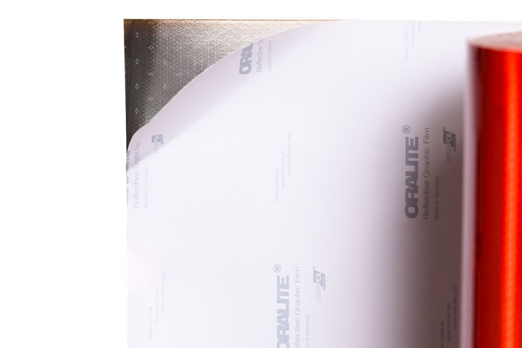 Abgezogenes Schutzpapier auf der Rückseite der fluoreszierend rotorangenen ORAFOL VC 612 Reflexfolie