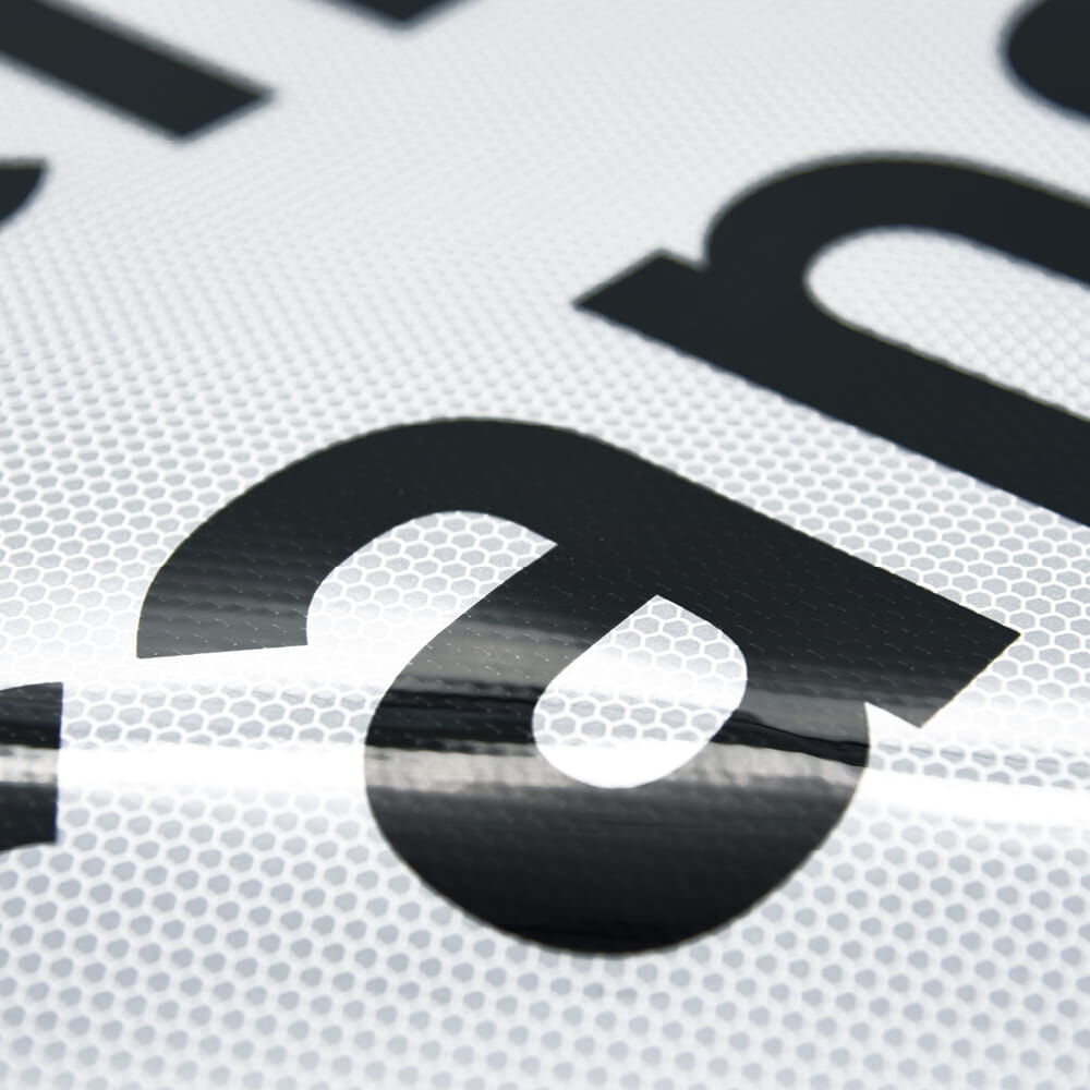 Nahaufnahme der schwarzen Schrift auf reflektierender Oberfläche des Schwertransportschilds