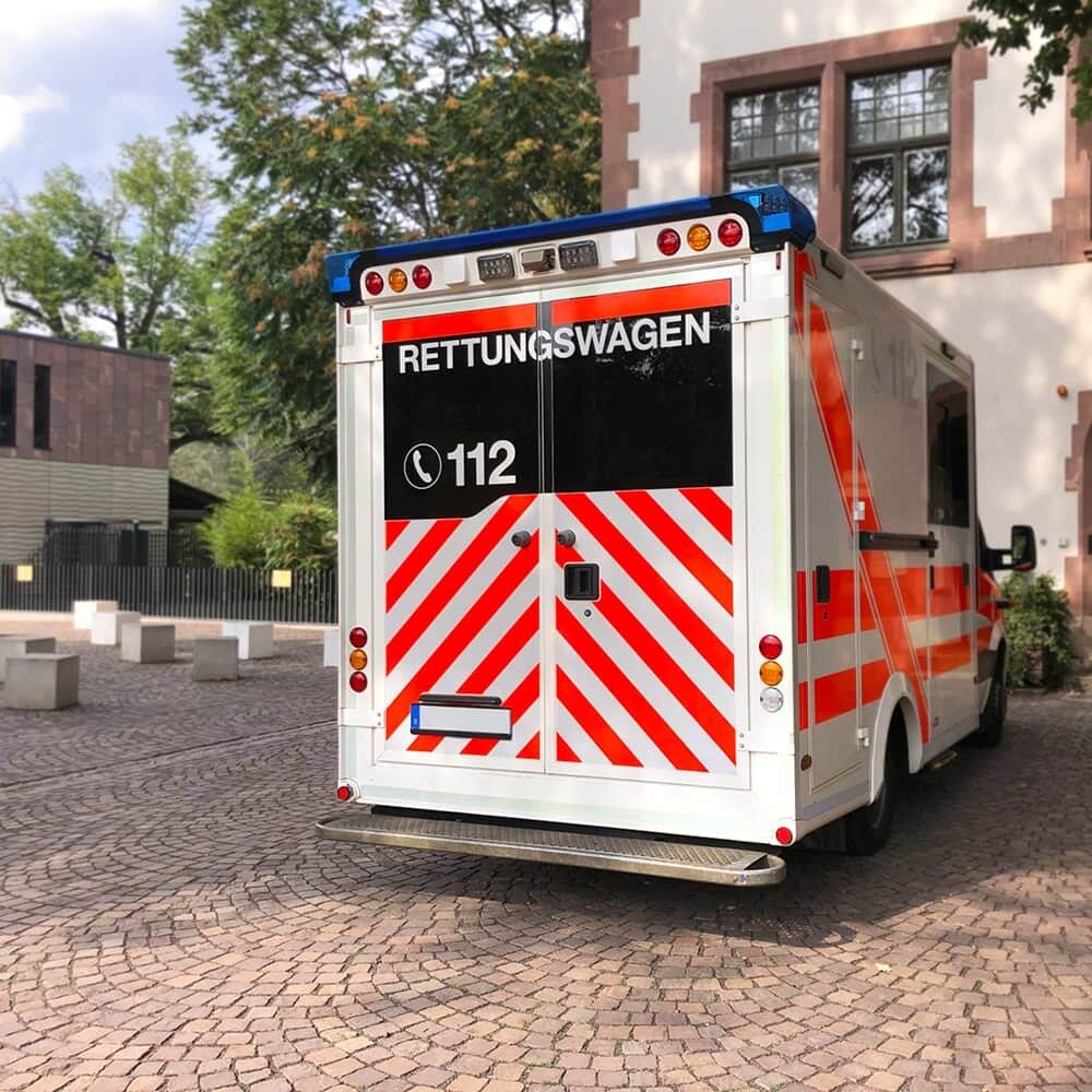 Rettungswagen bei Tag mit rot-weißer Heckwarnmarkierung aus ORACAL Fluorfolie 7510 Premium