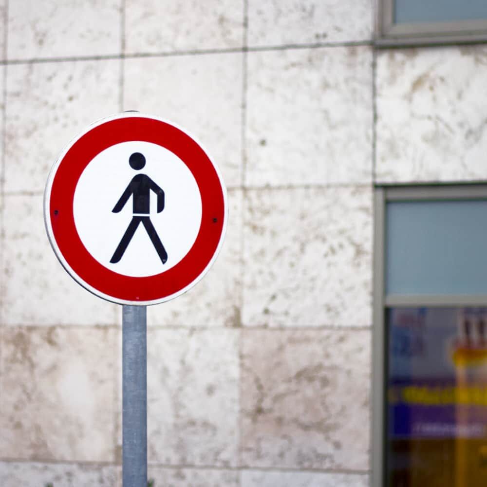 Verkehrszeichen „Verbot für Fußgänger“ an Mast vor Gebäude